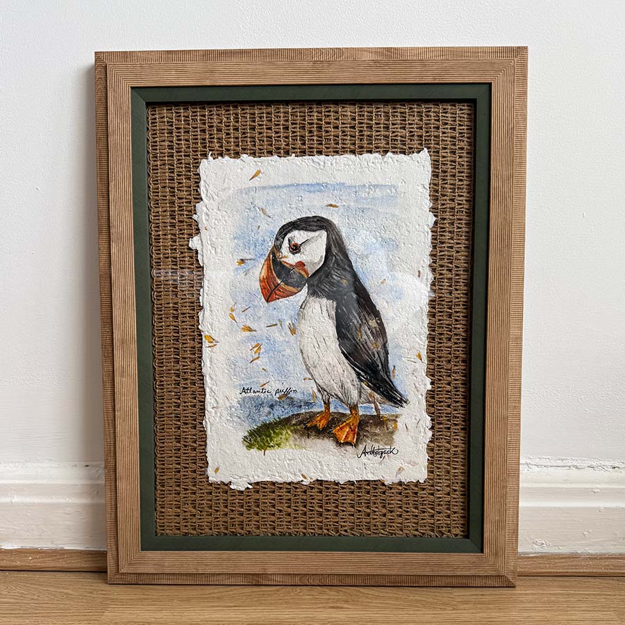 Framed artwork of a puffin on textured paper with a wicker background