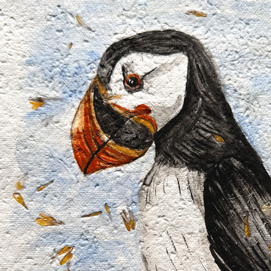 Illustration of a puffin with seaweed in its beak on textured paper.