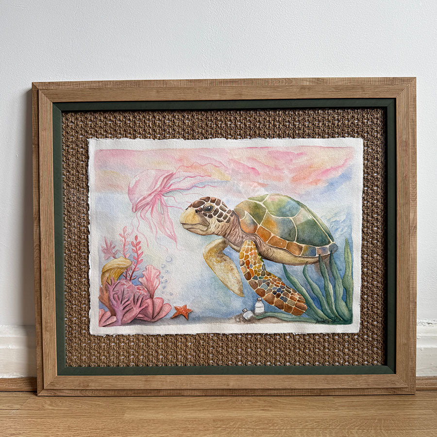 Framed artwork of a sea turtle and underwater scene on a textured wall.
